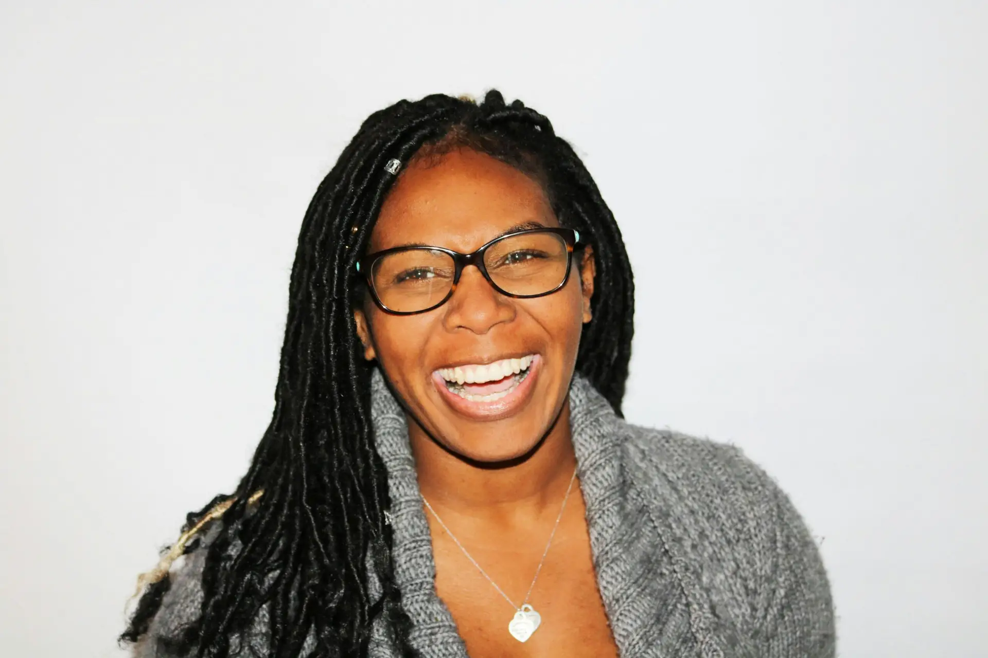 A vibrant portrait of a smiling woman with dreadlocks and glasses, exuding joy. She practiced mindfulness to eliminate anxiety and stress.